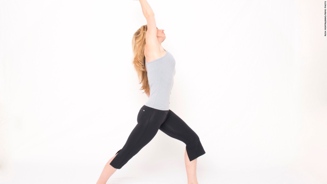From standing, step your right foot back, as though coming into a lunge, but place your heel down with your toes angled slightly out. Bend your left knee to align above your ankle. Keep your back leg straight. Place your left hand on your left hip. If balance is a challenge, place your left hand on a wall or other support. Inhale as you reach your right arm overhead to the left, stretching your right side and front of your hip. Avoid arching your low back. Hold the stretch for a few breaths. Repeat on the opposite side.