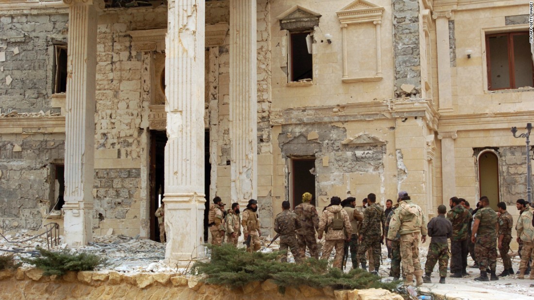 Syrian troops stand next to a mansion belonging to the Qatari royal family on March 24.