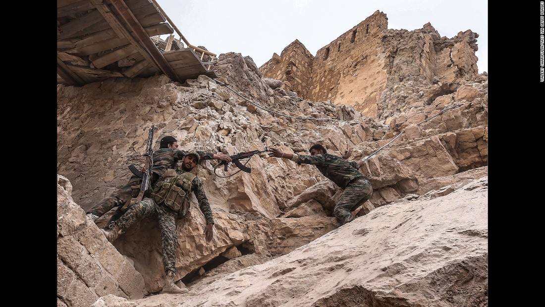Syrian soldiers climb to the top of the castle to place a flag on March 26.