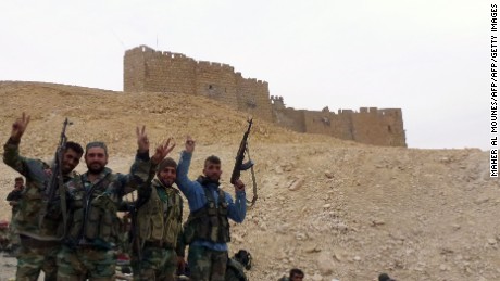 Syrian pro-governement forces gesture next to the Palmyra citadel on March 26, 2016, during a military operation to retake the ancient city from the jihadist Islamic State (IS) group. / AFP / Maher AL MOUNES        (Photo credit should read MAHER AL MOUNES/AFP/Getty Images)