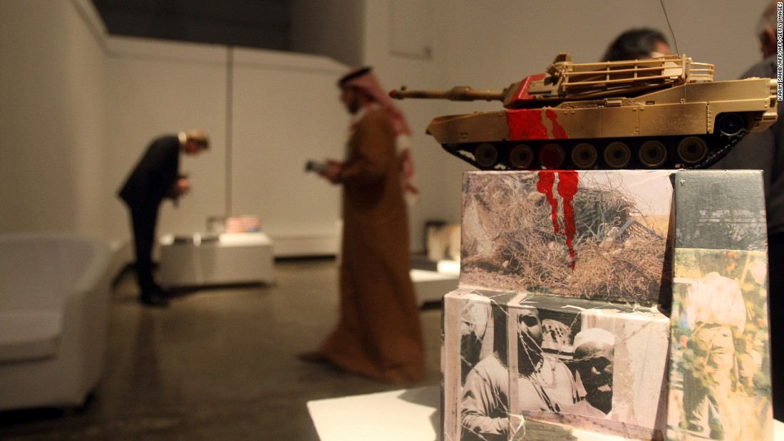 Visitors look at an artwork entitled &quot;The Ugly Face of Occupation 2009&quot; by Iraqi artist Dia Azzawi displayed at &quot;My Home Land&quot; exhibition in Dubai in 2010. Seven Iraqi artists living outside Iraq took part in the exhibition. 