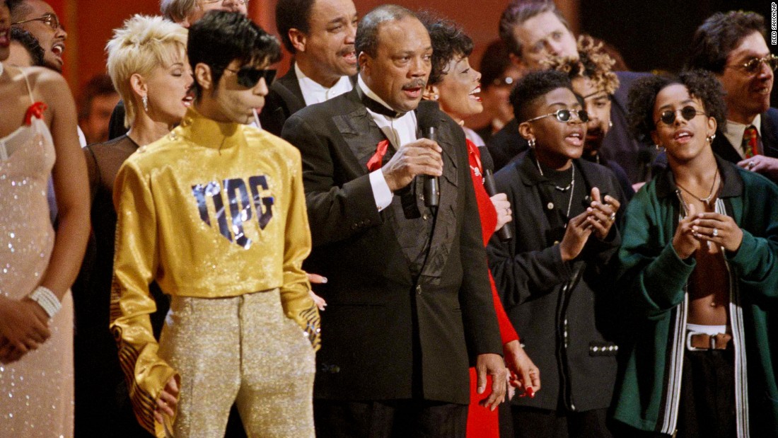 As dozens of singers perform &quot;We Are The World&quot; on the 10th anniversary of the African famine relief anthem, the artist formerly known as Prince stands sucking on a lollipop next to Quincy Jones at the American Music Awards in Los Angeles in 1995.
