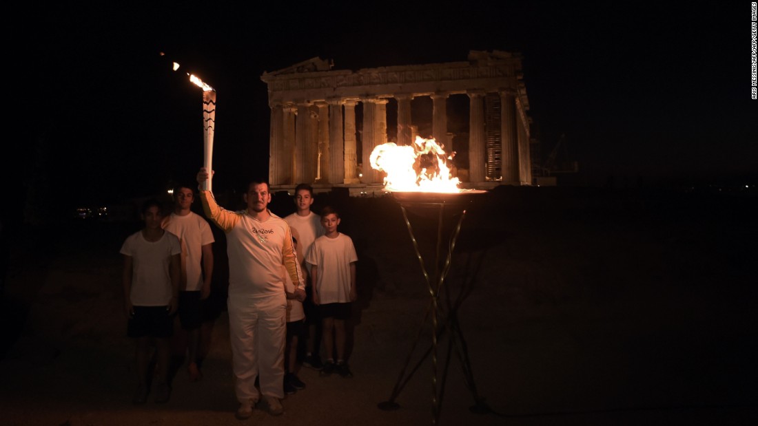 Greek former Olympic weightlifting gold medalist Pyros Dimas also held the torch, and stands here atop the Acropolis hill by the the ancient temple of the Parthenon, after lighting a cauldron with the Olympic flame. 