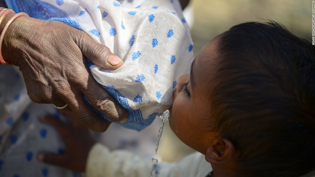 A woman tries to filter water with her sari as a child drinks in the Shankargarh area on April 21.