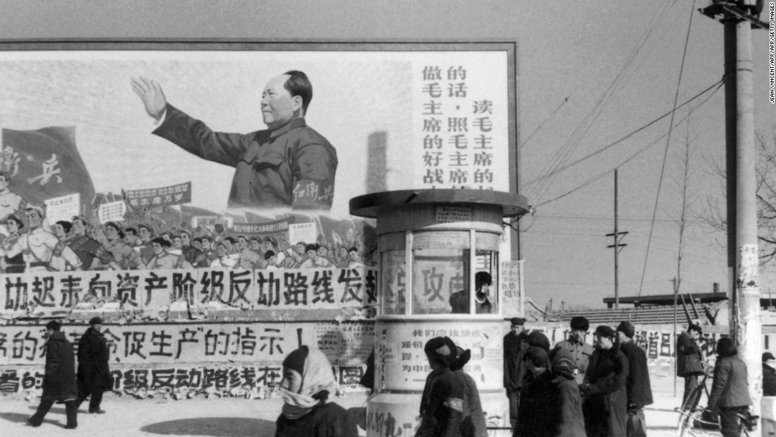 Beijing residents walk past a huge poster of Mao during the Cultural Revolution. The poster calls on people &quot;to be good soldiers of Mao Zedong.&quot;