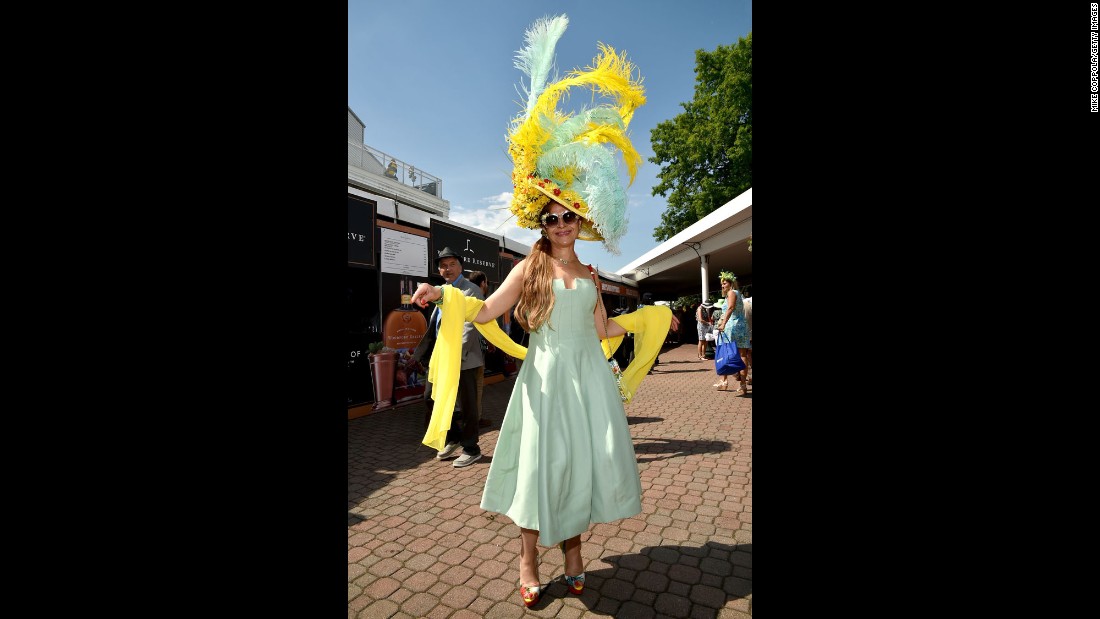 A fan shows off her feather-and flower adorned hat. 