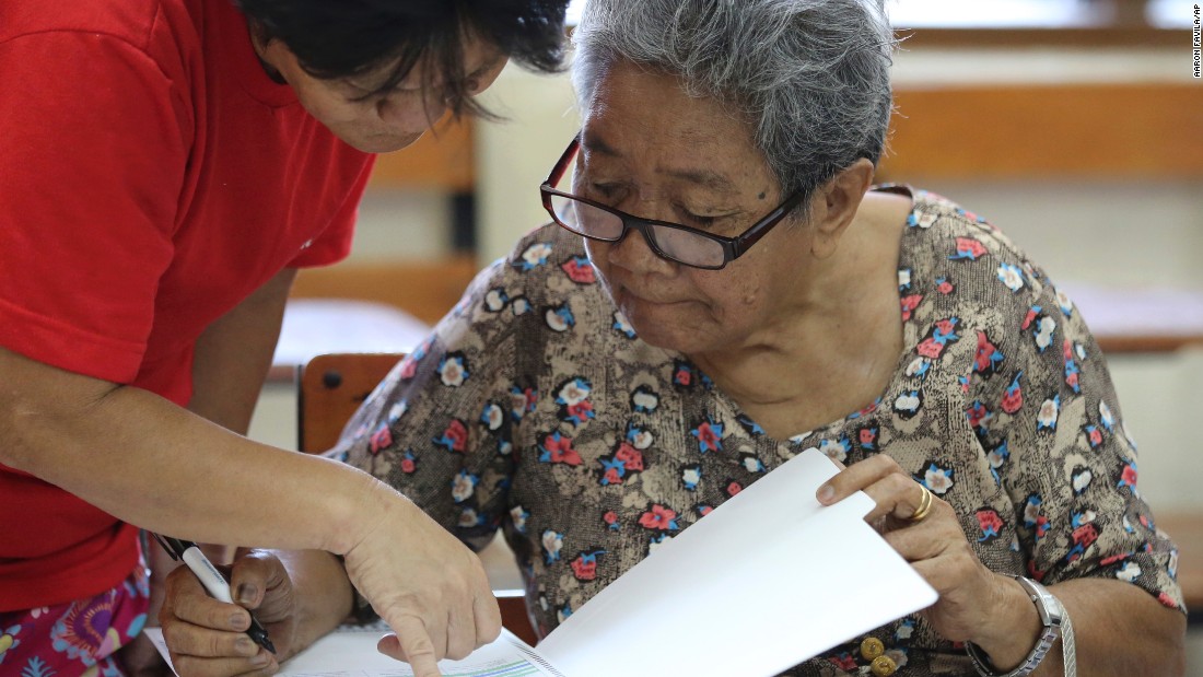 Eighty-year-old Dioleta Esteban is assisted as she votes at a polling center in suburban San Juan, east of Manila, Philippines on Monday, May 9, 2016. 