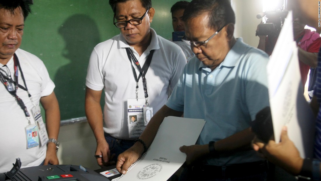 Presidential candidate and current Philippine Vice President Jejomar Binay (right) inserts his ballot into the vote counting machine inside a polling center at the San Antonio National High School in Makati, Philippines on May 9, 2016. 