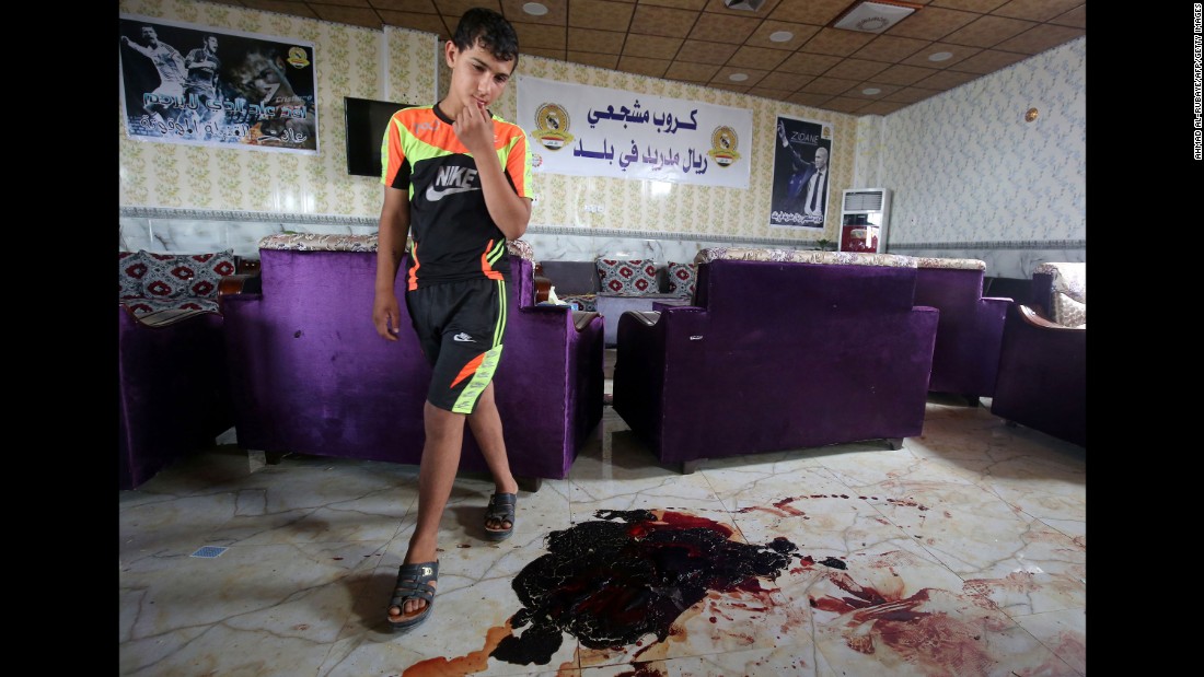 A boy walks past bloodstains and debris at a cafe in Balad, Iraq, that was attacked by ISIS gunmen on May 13, 2016. Twenty people were killed.