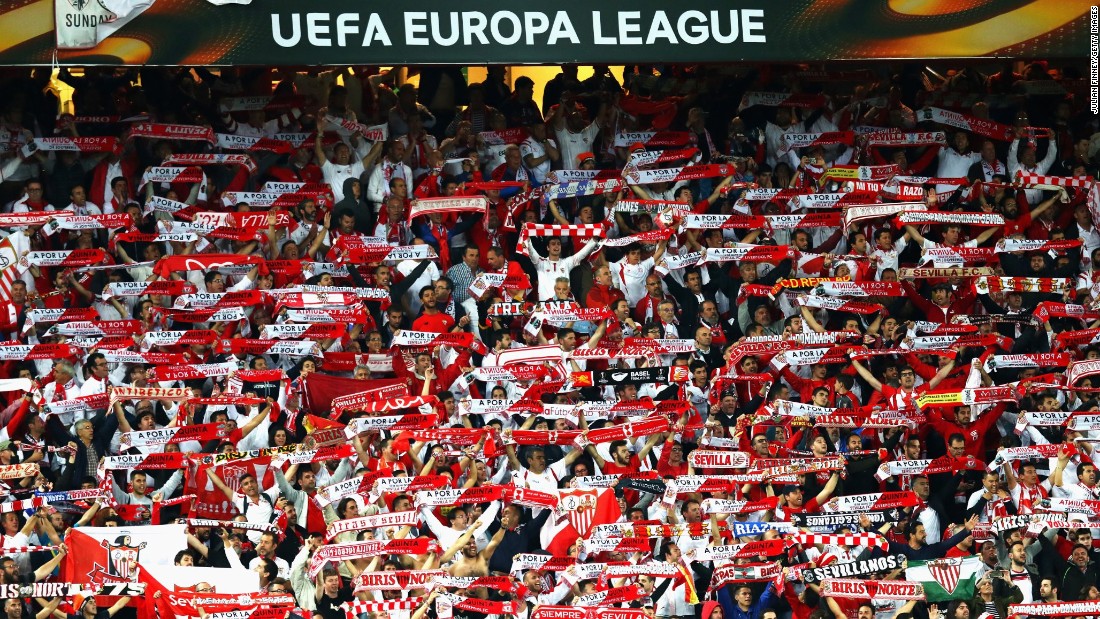 Sevilla supporters cheer and hold up scarves as it becomes clear their team is about to claim another Europa League success.