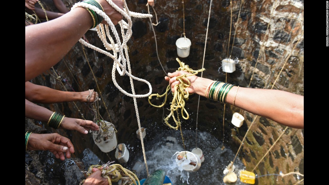 Villagers in Shahapur throw containers into a well on May 13.