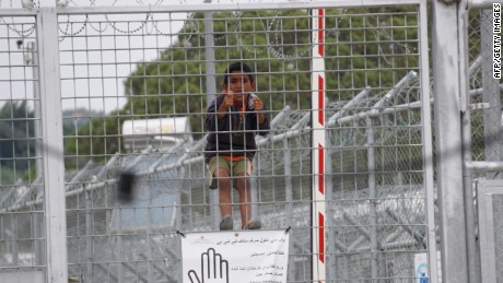 A child looks through the fence at the Moria detention camp for migrants and refugees at the island of Lesbos on May 24, 2016. 