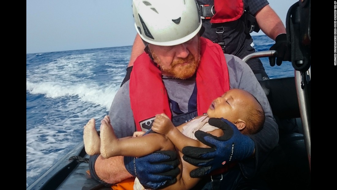 A member of the humanitarian organization Sea-Watch holds a migrant baby who drowned following the capsizing of a boat off Libya in May 2016.