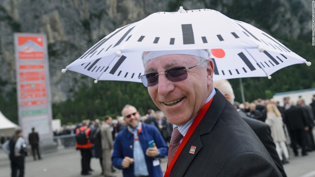 A guest poses with an umbrella decorated with the Swiss Rail clock logo before the opening ceremony of the Gotthard Base Tunnel.