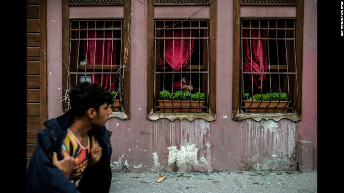 A man walks past a building with broken windows from the blast.