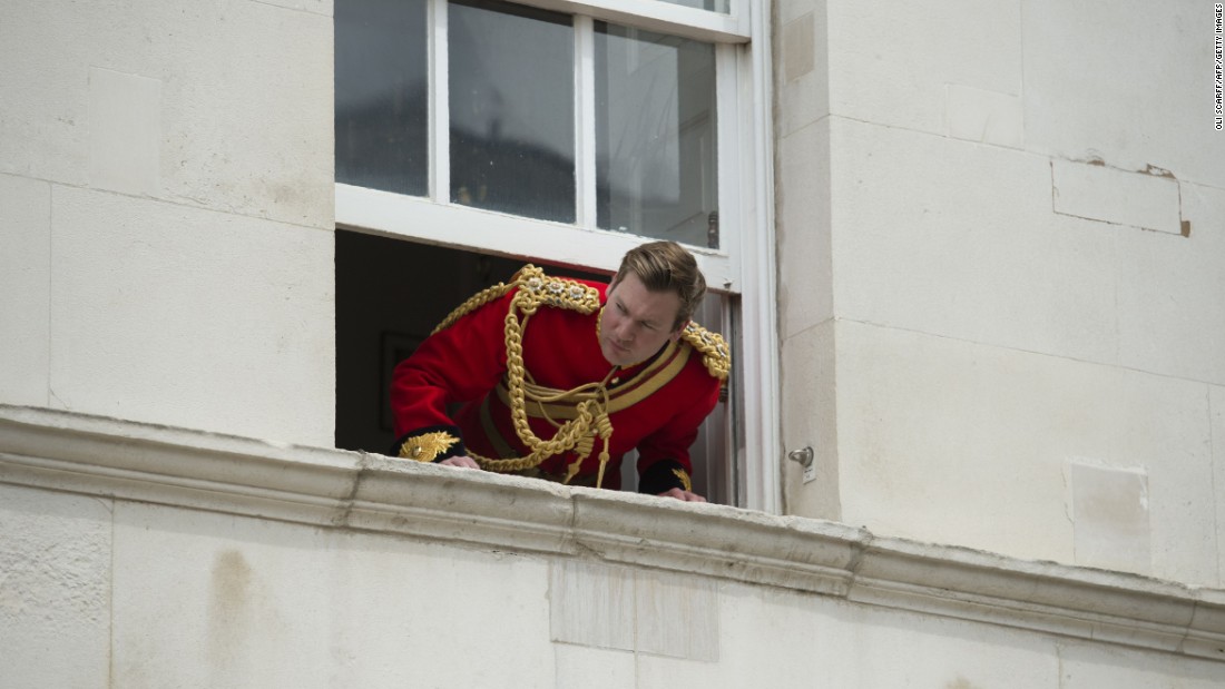 A soldier looks out of an upper floor window to watch the parade.