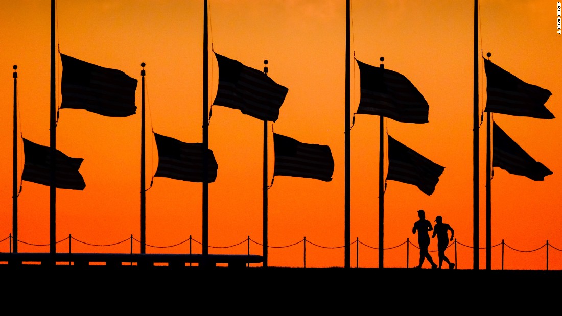 Runners pass under half-staff flags at the Washington Monument on June 13.