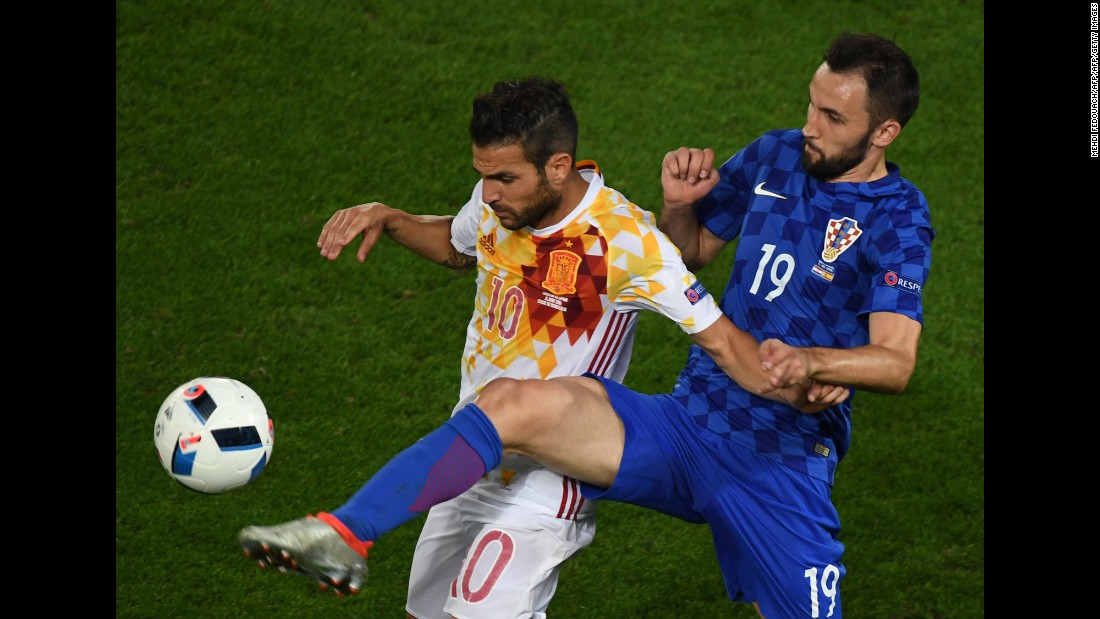 Spanish midfielder Cesc Fabregas tries to shield the ball from Milan Badelj.