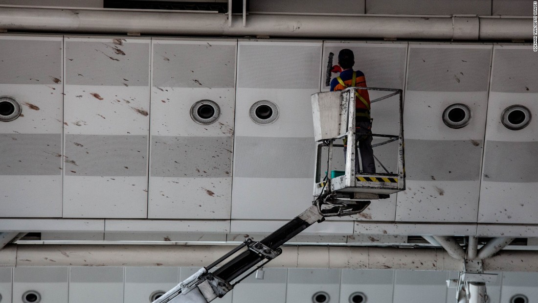 A worker cleans blood from the upper walls of the international departure terminal.