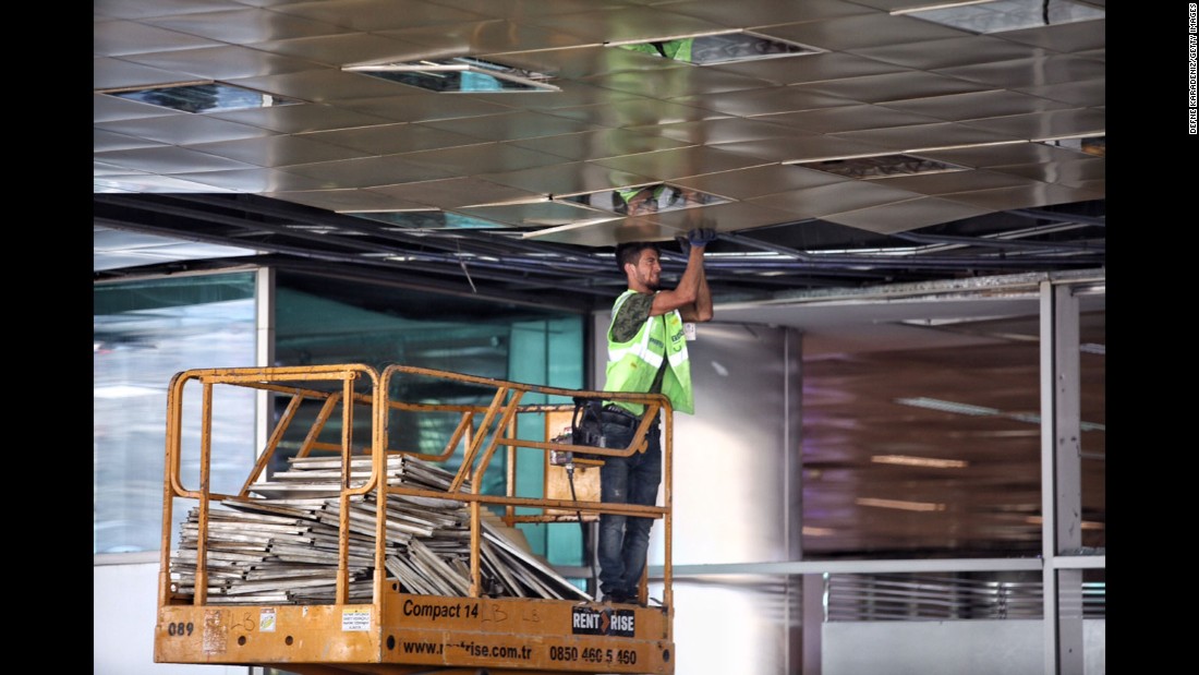 A worker repairs the airport&#39;s damaged ceiling on June 29.