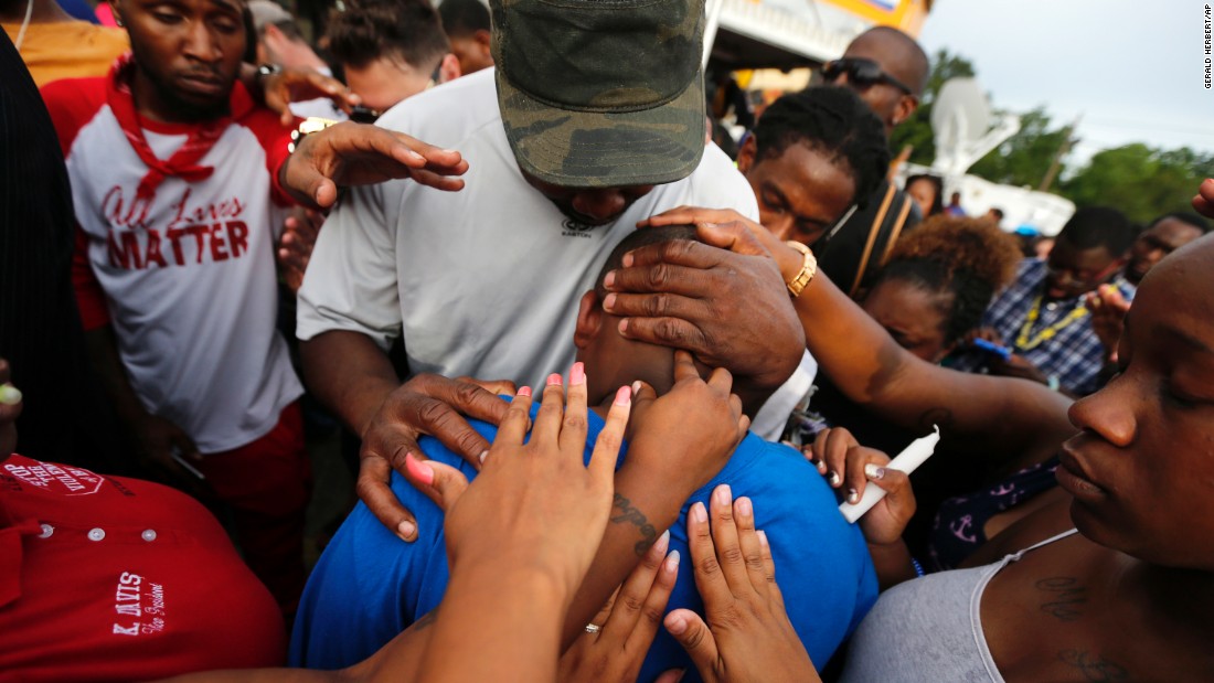 One of Sterling&#39;s children, Cameron, is comforted by a crowd outside the convenience store on July 6.