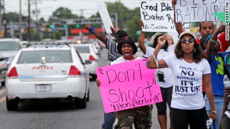 People demonstrate in the street as police cars pass outside the Triple S convenience store during a rally after Alton Sterling, a black man, was shot and killed Tuesday, in Baton Rouge, La., Wednesday, July 6, 2016. The U.S. Justice Department opened a civil rights investigation Wednesday into the video-recorded police killing of Sterling, who authorities say had a gun as he wrestled with two white officers on the pavement outside a convenience store. (AP Photo/Gerald Herbert)