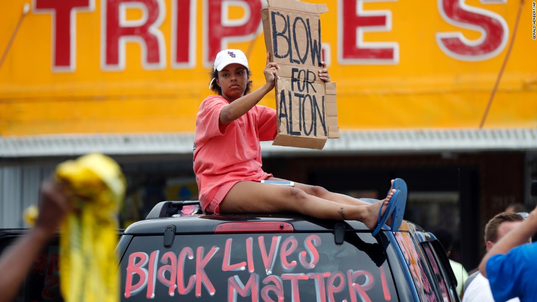 Jordan Nuerenberg holds up a sign encouraging motorists to honk their horns outside the Baton Rouge convenience store.