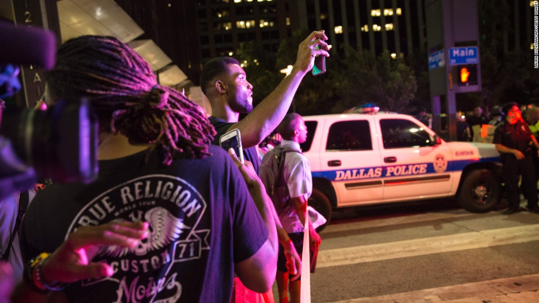 Onlookers stand near police barricades after the shootings. 