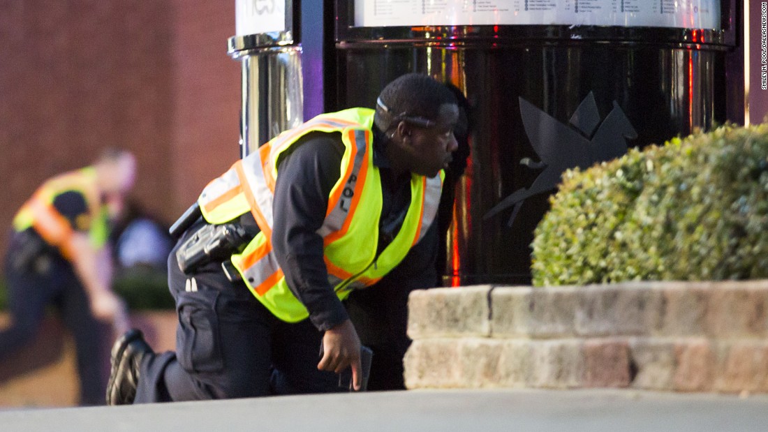 Two officers crouch behind barriers.