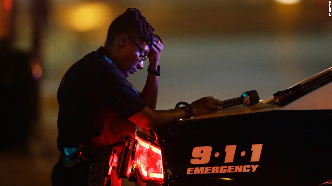 A Dallas police officer takes a moment as she guards an intersection in the early morning hours.