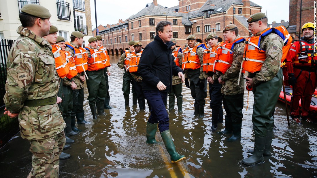 Cameron puts on a pair of wellington boots after severe flooding hit large parts of northern England in December 2015. 