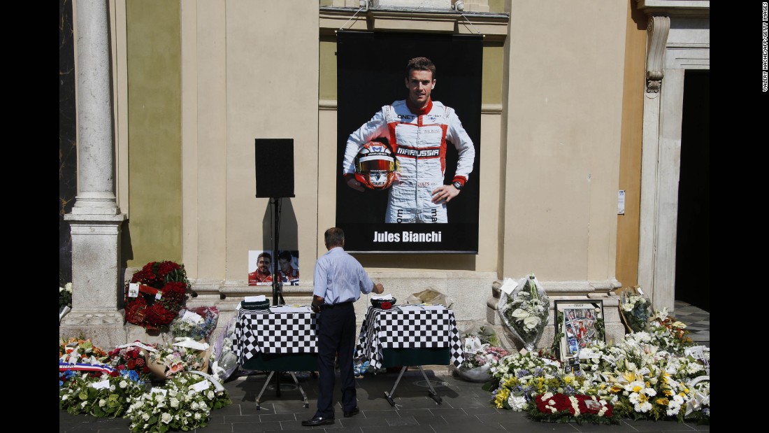 A man pays his respects below a poster showing Bianchi, after the driver&#39;s funeral ceremony at the Cathedrale Sainte Reparate in Nice on July 21, 2015, in southeastern France.