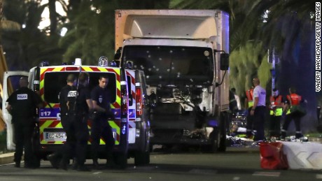 Police officers and rescued workers stand near a van that ploughed into a crowd leaving a fireworks display in the French Riviera town of Nice on July 14, 2016. 