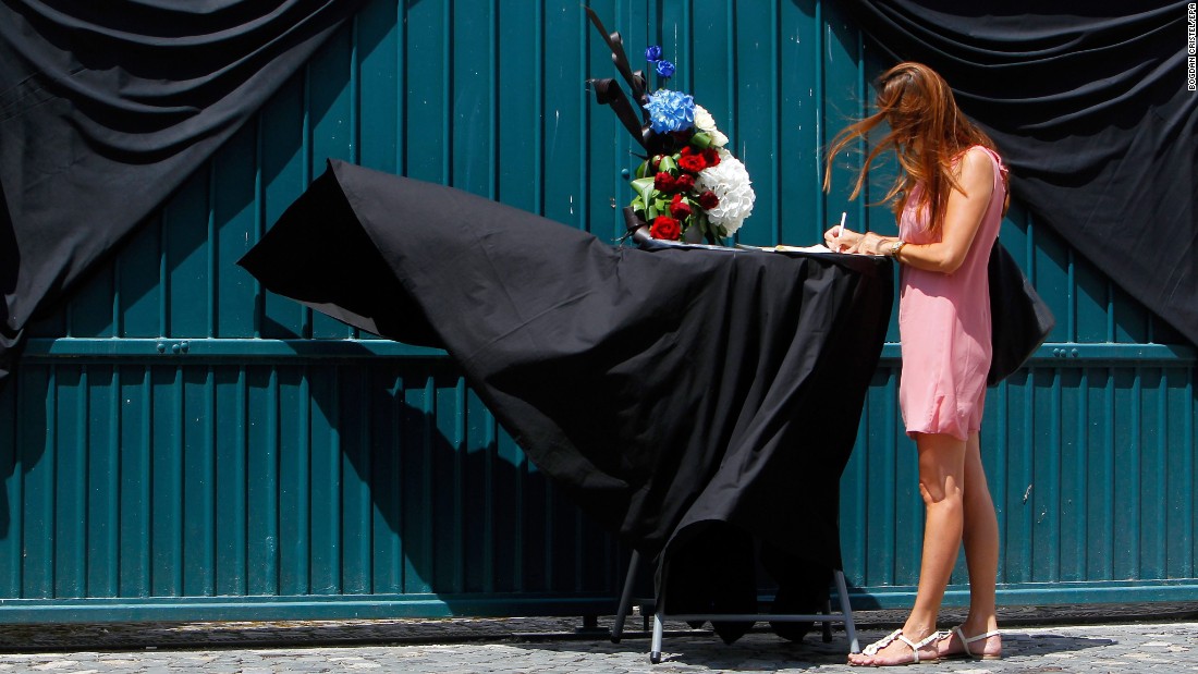 A woman signs a condolence book in front of the French Embassy in Bucharest, Romania.