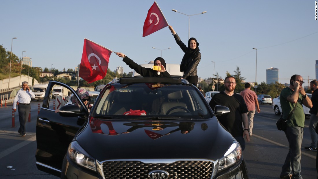Turkish people wave national flags from a car in Istanbul.
