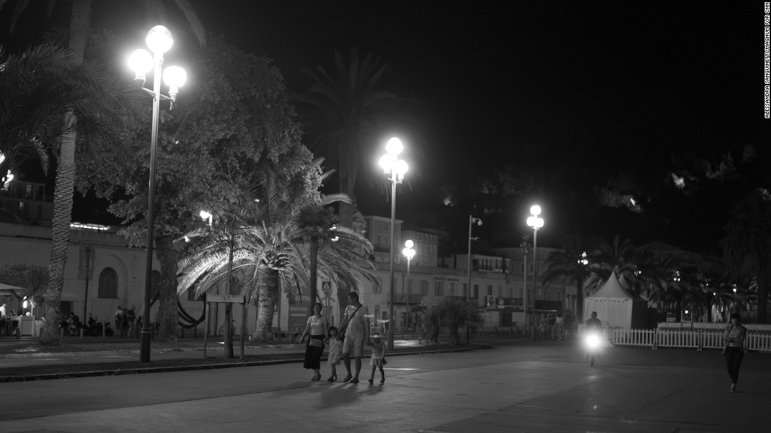 People hold hands as they walk on the Promenade des Anglais.