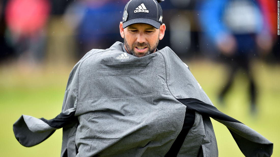 Spain&#39;s Sergio Garcia protects himself from the elements during his third round of 73 to go into the clubhouse on 211 -- two under.