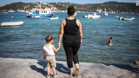 Damla, an unemployed high school dropout, hold&#39;s her son&#39;s hand as she poses for a photo next to the Bosphorous, in Istanbul. 