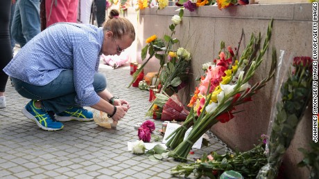 People lay flowers and candles outside the OEZ shopping center the day after a shooting spree left nine victims dead on Saturday, July 23 in Munich, Germany. 