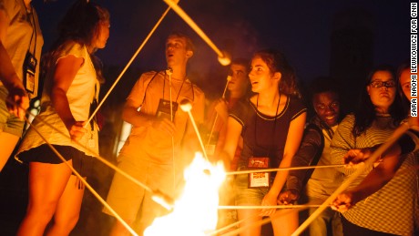 Campers at the retreat roast marshmallows over a fire together.