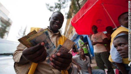 A mobile phone credit seller counts his Rwandan franc currency notes on a street in Kigali.
