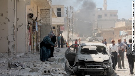 A woman inspects a damaged car after Russian planes carried out an airstrike over Etarib district of Aleppo, Syria.