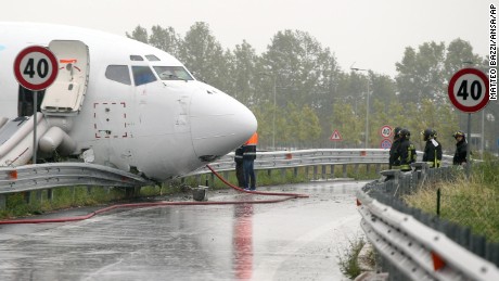 Firefighters work on a DHL cargo plane that skidded off a runway overnight at the airport of Bergamo Orio al Serio in northern Italy, crashing through a guard rail onto a highway on Friday, August 5.