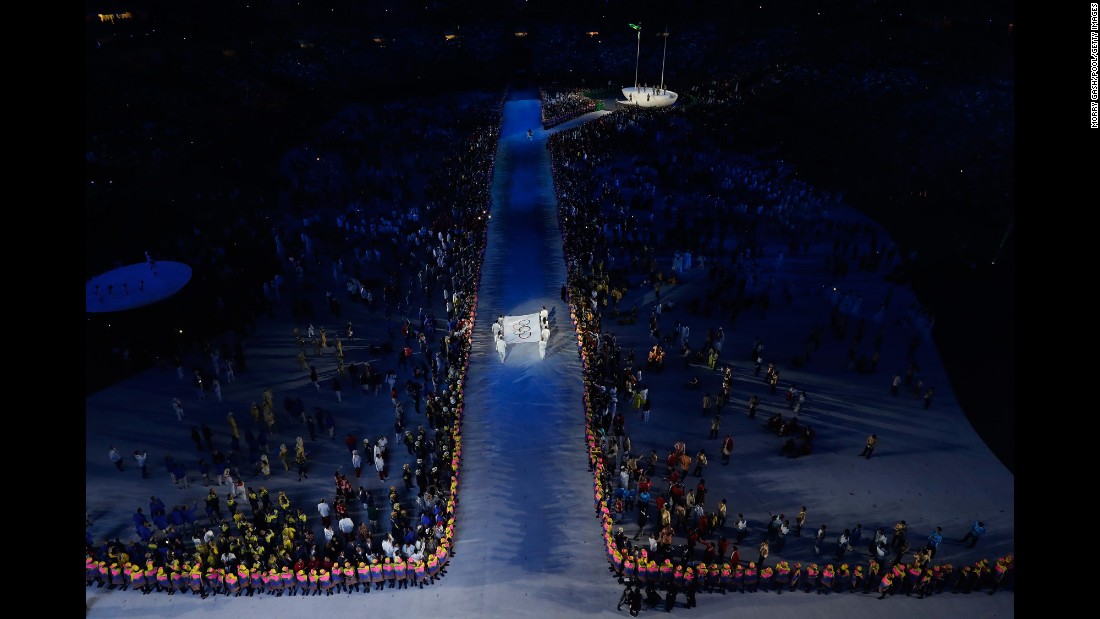 The Olympic flag is carried into the stadium.