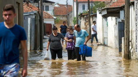 People wade through floodwaters on Sunday in the village of Stajkovci, near Skopje, Macedonia.