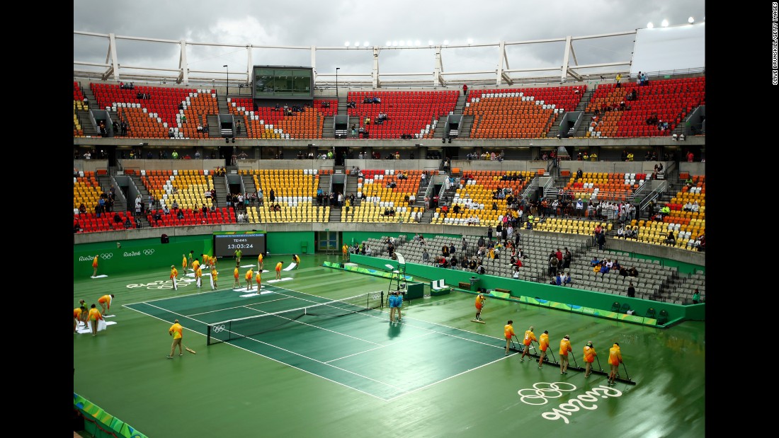 Volunteers dry a rain-soaked court at the Olympic Tennis Center.