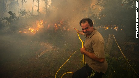 A man fights a wildfire with a garden hose in the Pontevedra region of northwestern Spain Thursday.