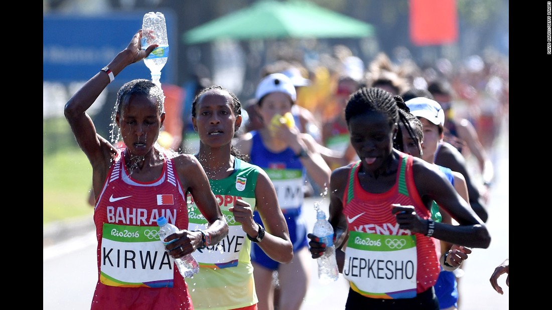 Eunice Jepkirui Kirwa of Bahrain tries to stay cool by pouring water on her head as she runs alongside Visiline Jepkesho of Kenya.