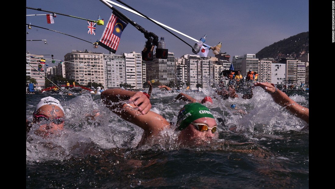 Refreshment bottles are held over women competing in the 10-kilometer open water swimming event.