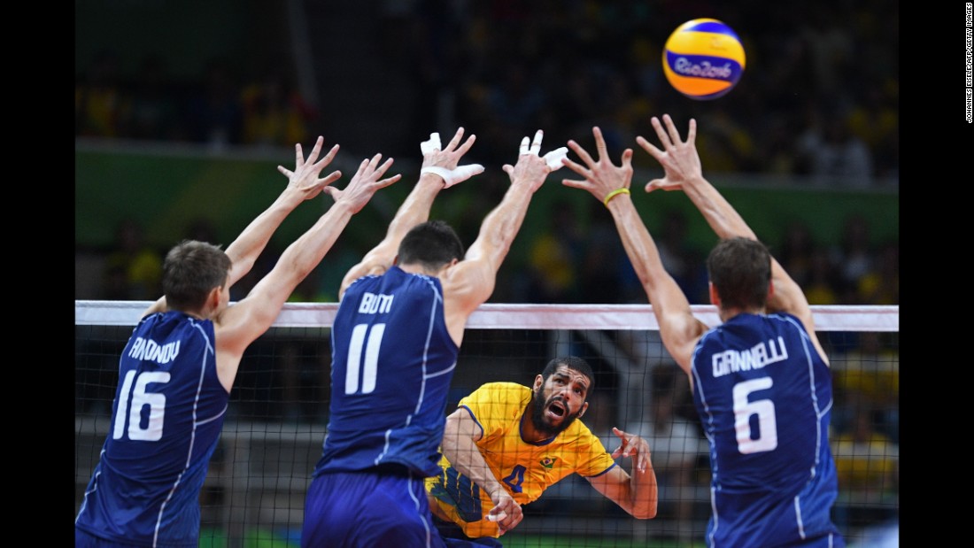 Brazilian volleyball player Wallace de Souza, in yellow, spikes the ball in the gold medal game against Italy. The Brazilians won.